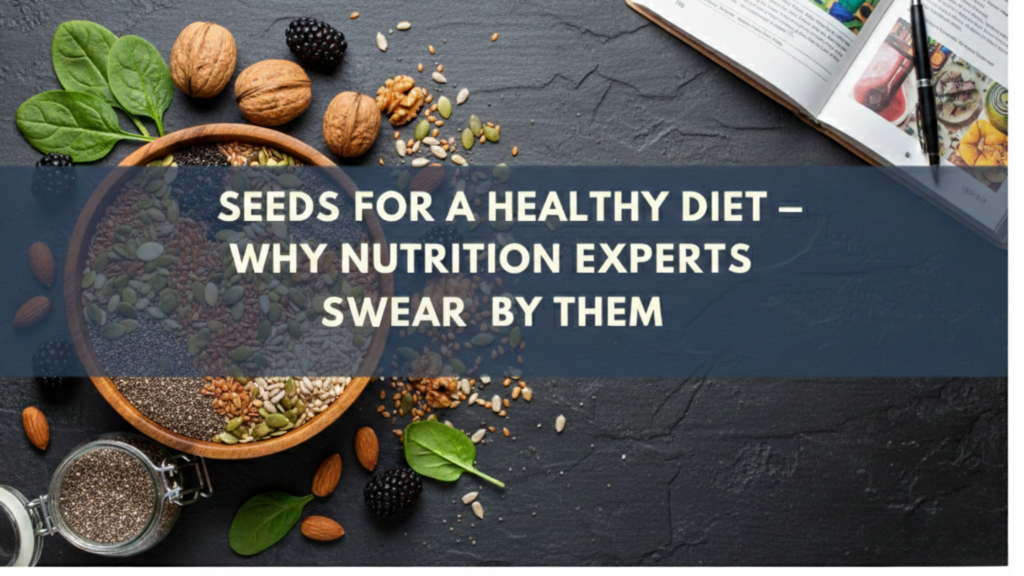 A top-down photographic view of various seeds and nuts—including chia, pumpkin, and flax seeds—arranged in a wooden bowl and glass jar on a dark slate background. A horizontal slate-blue banner across the center displays the text "SEEDS FOR A HEALTHY DIET – WHY NUTRITION EXPERTS SWEAR BY THEM" in bold, white capital letters.