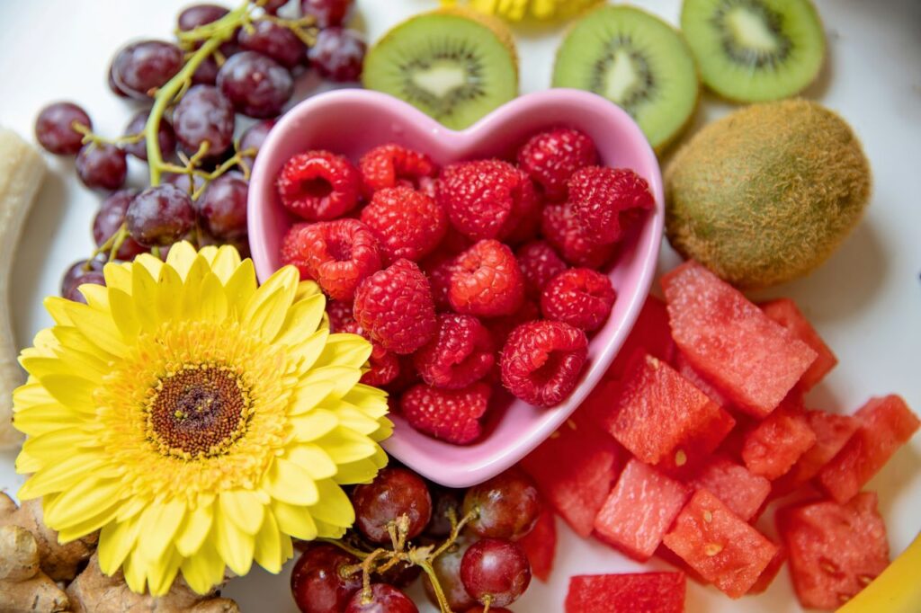 Heart-shaped bowl with fresh fruits promoting nutrition for heart health and cholesterol management diet.